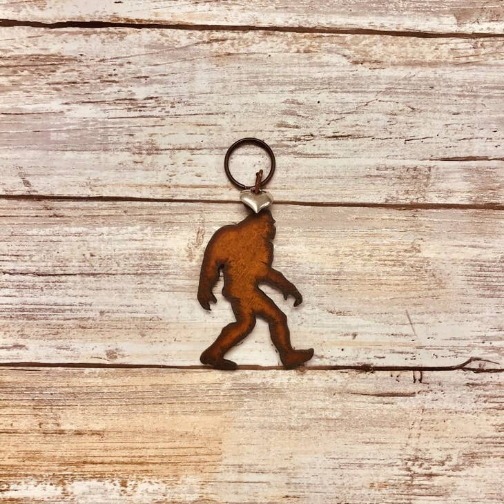 Rusty metal Bigfoot keychain with silver heart charm attached