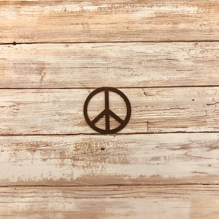 Rustic metal fridge magnet shaped like a classic peace symbol